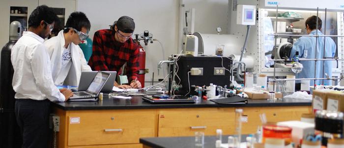 学生们和教授一起工作，周围都是化学设备.